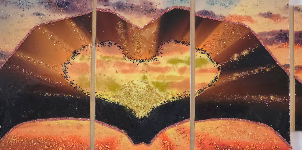 Close-up of the three centre panels of Sunset in Our Hands, focusing on the two hands forming a heart shape around the glowing sunset landscape.